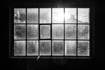 Dirty window in abandoned factory with sun shining through