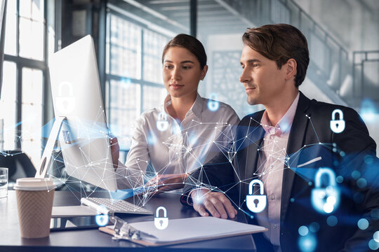 Businessman and businesswoman working together to protect clients confidential information and cyber security. IT hologram padlock icons over office background with panoramic windows.