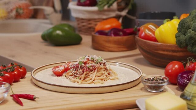 Close up tracking shot of female hands putting plate with homemade spaghetti bolognese on kitchen table
