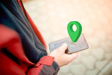 Online navigation, GPS and Geocaching. Green geolocation sign above the smartphone screen with an...