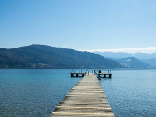 Panoramic view of Lake Attersee with wooden pier and mountain range in the background. Salzkammergut Upper Austria