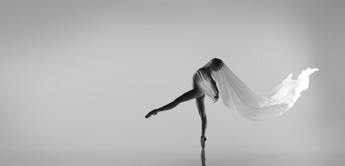 Black and white portrait of graceful ballerina dancing with fabric, cloth isolated on grey studio background. Grace, art, beauty concept. Weightless, flexible. - obrazy, fototapety, plakaty