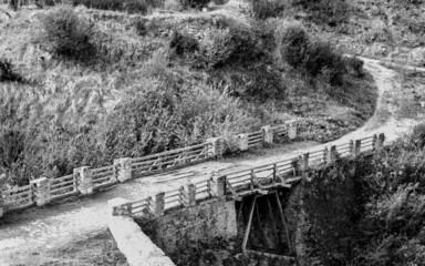 Black and white concept photo of an old wooden bridge crossing on a country road