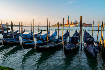 Fototapeta na wymiar Venice, Italy - July 28 2021: Canals with boats and gondolas in Venice, Italy during sunrise