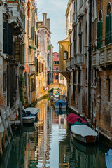Fototapeta na wymiar Venice, Italy - July 28 2021: Narrow canals with boats and gondolas in Venice, Italy