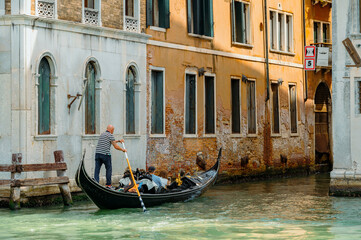 Obraz na płótnie Canvas Venice, Italy - July 28 2021: Narrow canals with boats and gondolas in Venice, Italy