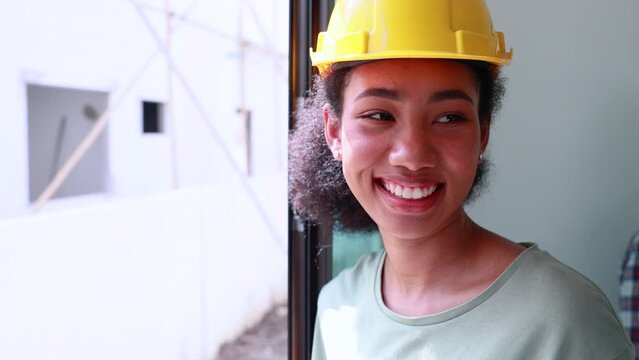 close up face black woman. portrait femal african american engineer worker wearing yellow hard hat helmet working on construction site.