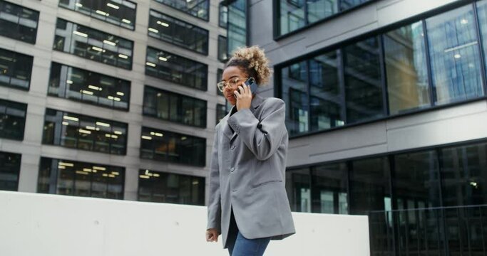 A woman using mobile phone while standing near an office building