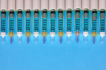 Syringe pens with insulin lined up in a row on a blue background
