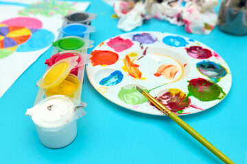 Plastic palette to mix colors and paint brush on a blue table