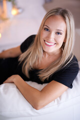 The smile that melted a million hearts. Portrait of a young blonde woman sitting on her sofa at home.