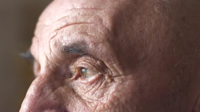 Close-up of the tired sad eyes of a Caucasian elderly man 70 years old looking into the distance. The pensioner is sad and waiting for his relatives. Loneliness and longing of a pensioner.
