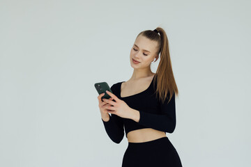 Naklejka premium Portrait of a pretty young woman listening to music with headphones and mobile phone isolated over white background