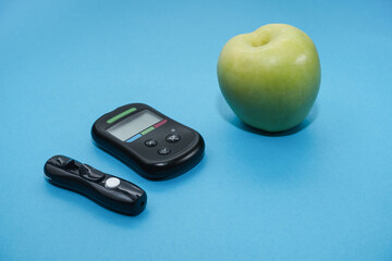 Diabetes concept. Glucose meter, apple on a blue background.