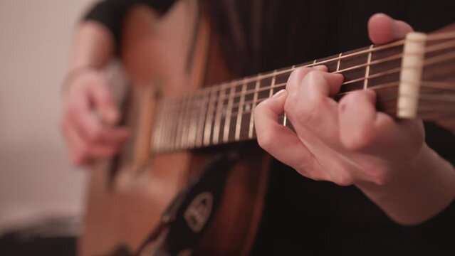 Acoustic guitar fretboard and hand playing chords, close up view with no face
