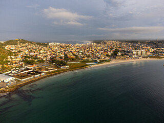 Fototapeta premium Amazing sunset on a paradise beach with mountains, nature and city. Drone aerial view. Arraial do Cabo, Rio de Janeiro, Brazil