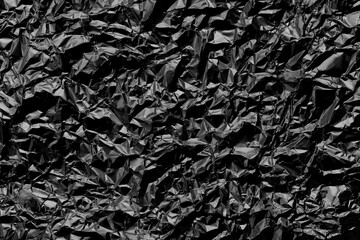 Shiny black foil texture background, pattern of wrapping paper with crumpled and wavy.