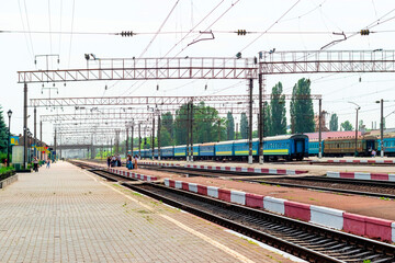 Railway trains with carriages and people on the platform of the railway station