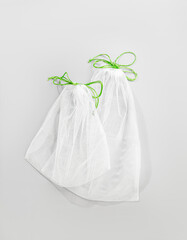 two white eco bags with ties for buying vegetables and fruits in the store, zero waste mesh shopping bags, weighing bag