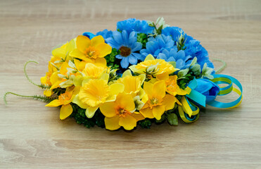 Wreath of decorative flowers, with Ukraine flag ribbon on wooden background. Symbol of the strength and beauty of the Ukrainian people.