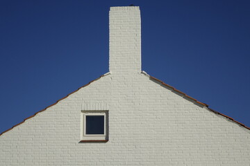 White brick stone house gable under a blue sky, use: background, copy space (horizontal),...
