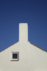 White brick stone house gable under a blue sky, use: background, copy space (vertical), Zandvoort,...