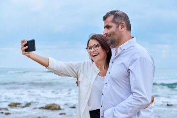 Happy mature couple taking selfie photo on smartphone.