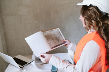 professional architect woman in construction site working on blueprints. Home renovation