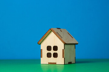 Obraz na płótnie Canvas Small wooden toy house on a colored background. Real estate purchase and sale concept. real estate services