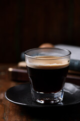Coffee in glass cup on dark wooden background. Close up.
