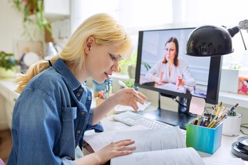 Teenage girl studying at home online using computer