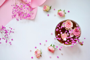 Flower arrangement of small roses and gypsophila. Cup and pink background