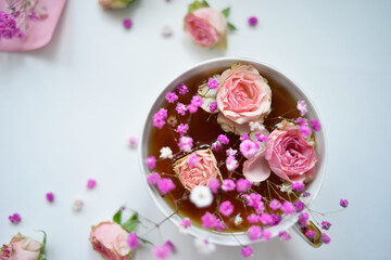 Flower arrangement of small roses and gypsophila. Cup and pink background