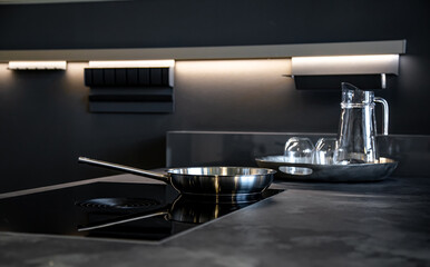 Frying pan in the interior of the kitchen in black, modern style.