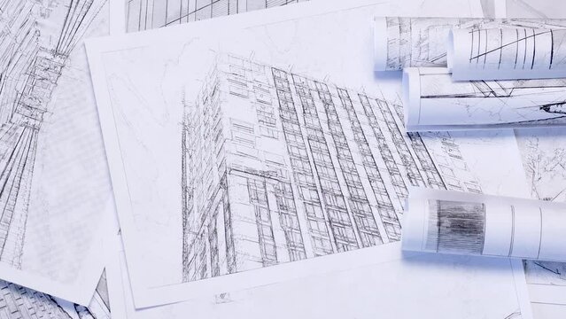Background on the theme of business in the field of construction and architecture. Sheets with drawings and sketches of a glass skyscraper in soft focus.