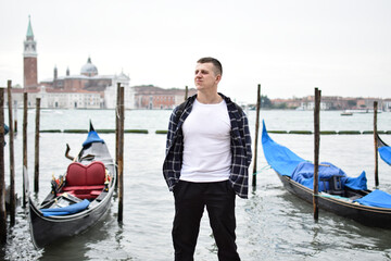 Fototapeta na wymiar Young guy tourist near the gondola in Venice