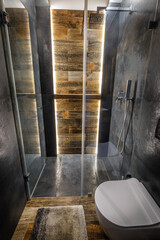 Stylish dark bathroom interior with shower. Tiles imitating wood on the floor and on the wall