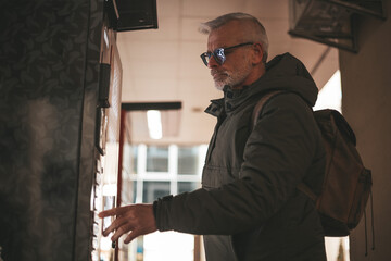 Street vending machine and customer. Mature man chooses and buys goods.