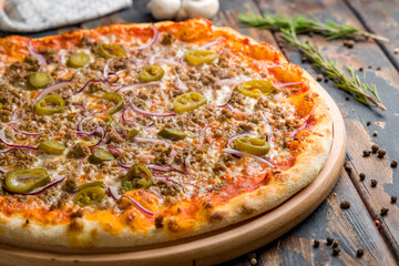 Mexican pizza with meat and jalapeno on old wooden table macro close up