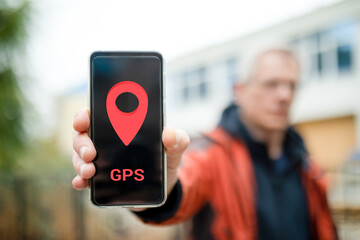 A man's hand showing a smartphone screen with a geolocation sign and the inscription GPS. The...