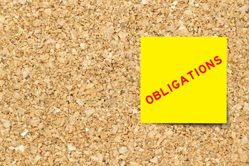 Yellow note paper with word obligations on cork board background with copy space
