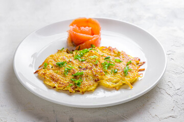 Fried potato pancakes with salted salmon on white plate macro close up