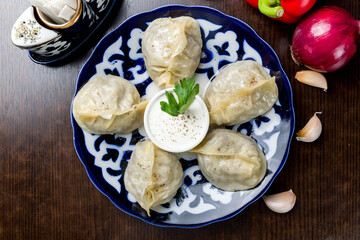 Manty with beef and sour cream top view on wooden table, Uzbek cuisine