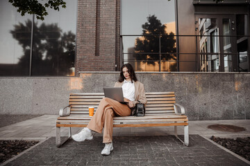  Tall stylish girl with oversized jacket sitting on the bench of the city background