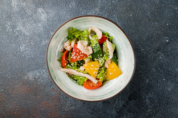 salad with citrus and squid on plate on dark concrete table top view