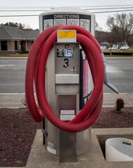 A red vacuum hose is coiled and ready to be used to clean someone's car for $2.  Prices to vacuum a...