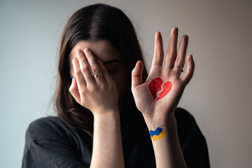 Ukrainian girl with a broken heart drawn on her hand, pain for Ukraine.
