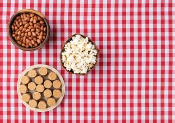 Peanuts, popcorn and pacoca, typical brazilian june festival food over plaid fabric with copy space