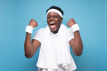 Naklejka premium Young african man shaking fists up isolated on blue background