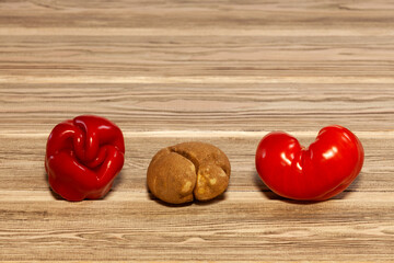 Ugly vegetables. Crooked red pepper, potato and tomato on wooden background. Reduction organic food...